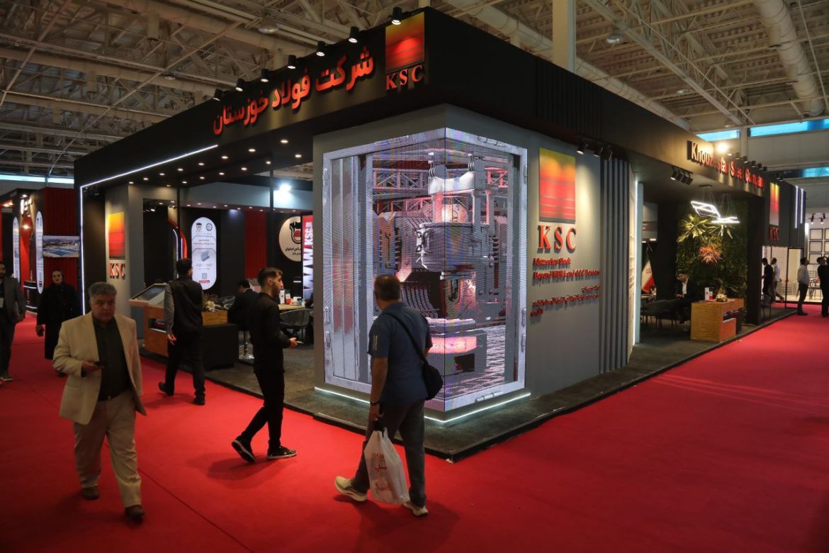 تصویری از مدیران و کارشناسان شرکت فولاد خوزستان در غرفه اختصاصی ایران اکسپو ۲۰۲۵ در حال مذاکره با تجار بین‌المللی و معرفی دستاوردهای صادراتی.